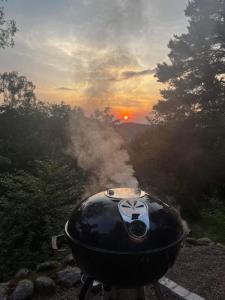 a grill with smoke coming out of it with the sunset at Chalet la parenthèse in Le Tholy