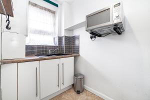 cocina con armarios blancos y TV en la pared en Comfortable 1BR flat in Canary Wharf en Londres