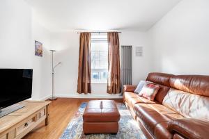 sala de estar con sofá de cuero y TV de pantalla plana en Comfortable 1BR flat in Canary Wharf en Londres