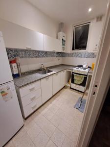 a kitchen with white cabinets and a sink and a stove at Departamento Peatonal in Mar del Plata