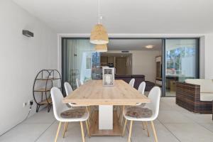 une salle à manger avec une table en bois et des chaises blanches dans l'établissement Luxury Apartment next to Golf Course in Marbella, à Marbella