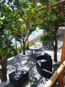 a patio with a table and chairs under trees at Villa Furoris Apartment in Furore