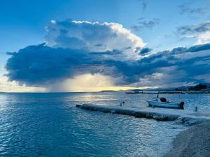 a boat on the beach in the water with a cloudy sky at Apartmani Mutogras in Podstrana