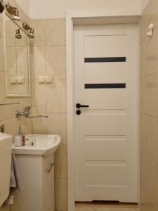 - une salle de bains avec une porte blanche à côté d'un lavabo dans l'établissement Apartament 51, à Gdynia