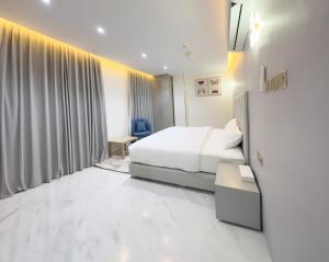 una camera bianca con un letto e una finestra di F&M Grand Hotel a Ibri