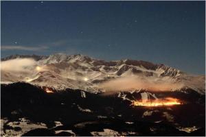 a snow covered mountain at night with a city at Appart 7 Laux - Balcon Sud in Les Adrets