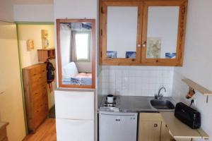 a small kitchen with a refrigerator and a sink at Appart 7 Laux - Balcon Sud in Les Adrets