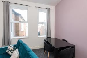 a living room with a couch and a desk and two windows at Rose Street in Monkwearmouth