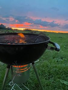 einen Grill auf einem Feld mit Sonnenuntergang im Hintergrund in der Unterkunft Saunamajutus Öötlas 