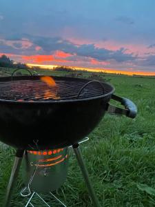 a grill in a field with a sunset in the background at Majutus saunaga majakeses in Öötla
