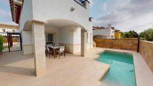 eine Terrasse mit einem Pool, einem Tisch und einem Haus in der Unterkunft Villa Jacaranda-A Murcia Holiday Rentals Property in Torre-Pacheco