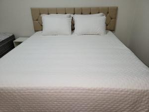 een bed met witte lakens en kussens in een kamer bij Madeira Lofts - Suite 01 in Juína