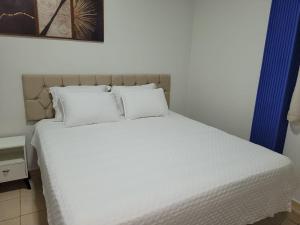 un letto con lenzuola e cuscini bianchi in una camera da letto di Madeira Lofts - Suite 01 a Juína