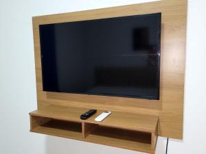 a flat screen tv with two remote controls on a shelf at Madeira Lofts - Suite 01 in Juína