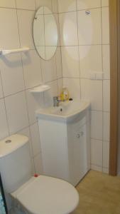une salle de bain blanche avec toilettes et lavabo dans l'établissement Vlados aprtamentai, à Palanga