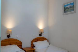 プラローニャン・ラ・ヴァノワーズにあるRésidence Goélia Le Blanchotのベッド2台 壁にランプ2つが備わる客室です。