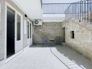 eine Terrasse mit 2 Stühlen und einem Tisch neben einer Steinmauer in der Unterkunft Vibrant Porto Apartments-Bonfim in Porto