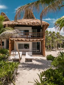 een huis op het strand met een rieten dak bij Niken Beachfront Tulum Hotel in Tulum