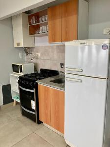 7-Exclusivo monoambiente en Moron centro في مورون: مطبخ مع ثلاجة بيضاء وموقد