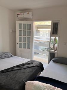 um quarto com 2 camas e uma porta para um pátio em Temporada em Cabo Frio em Cabo Frio