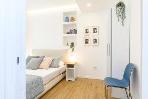 a white bedroom with a bed and a blue chair at Modern & Elegant by NDP Rent - NDP Rent in Rome