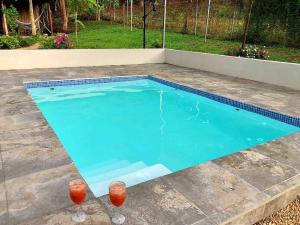 a swimming pool with two glasses in front of it at Cabaña Puerto Carrillo (Santa Marta) in Hojancha