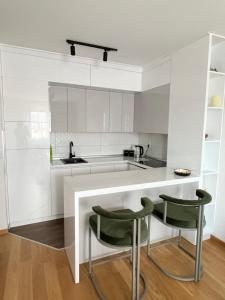 a kitchen with white cabinets and green chairs at Apartman 306 in Lukavica