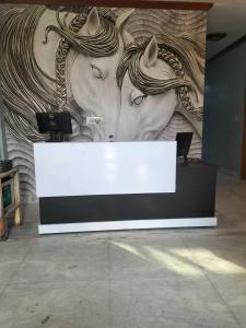 a counter with a mural of two horses on a wall at OYO 81311 Blue Moon In in Auraiya