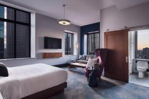 una camera da letto con un letto, un divano e una TV di Rand Tower Hotel, Minneapolis, a Tribute Portfolio Hotel a Minneapolis