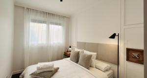 1 dormitorio con 1 cama blanca y ventana en Atico Duplex con terraza en Santander, en Santa Cruz de Bezana