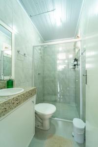 a white bathroom with a toilet and a shower at Chalés da Tribo in Bom Jardim da Serra