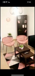 a living room with two pink chairs and a table at Vacation in the heart of the city netanya in Netanya