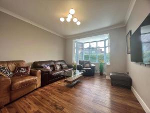ein Wohnzimmer mit einem Ledersofa und einem Tisch in der Unterkunft Cosy Modern Grimsby Home in Great Coates