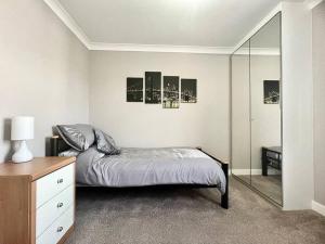 een slaapkamer met een bed, een dressoir en een spiegel bij Cosy Modern Grimsby Home in Great Coates