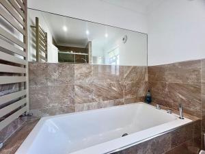 a large white tub in a bathroom with a mirror at Cosy Modern Grimsby Home in Great Coates