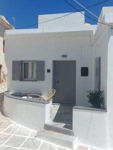 ein weißes Haus mit einem Stuhl und einer Tür in der Unterkunft Koutsounos in Kythnos