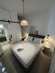 a bedroom with a large white bed and two lights at Koutsounos in Kithnos