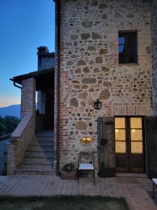 un edificio de piedra con un banco junto a una puerta en Podere San Selvatico en Città della Pieve