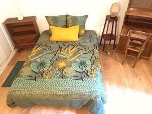- un lit avec une couette verte et un oreiller jaune dans l'établissement Maison Des Pas Enchantés, à Saint-Sébastien-sur-Loire