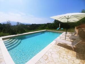 a swimming pool with an umbrella and two chairs at Podere San Selvatico in Città della Pieve