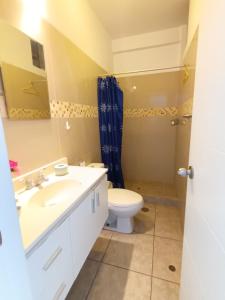 La salle de bains est pourvue d'un lavabo blanc et de toilettes. dans l'établissement Departamento en Punta Hermosa con vista al Mar, à Punta Hermosa