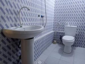 Baño blanco con lavabo y aseo en Kacho House, en Jambiani