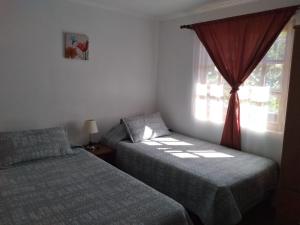 a bedroom with two beds and a window at Cabaña y Depto Puclaro in Vicuña