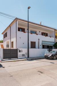 ein weißes Gebäude mit einem davor geparkt in der Unterkunft AS 10 HOUSE in Olbia