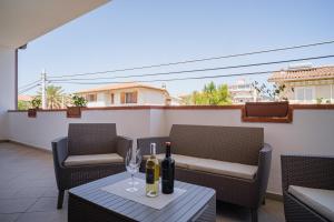 eine Terrasse mit 2 Stühlen und 2 Flaschen Wein in der Unterkunft AS 10 HOUSE in Olbia