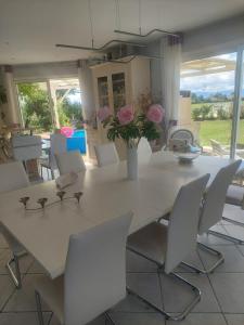 a white dining room table with white chairs and flowers at Villa Machilly in Machilly
