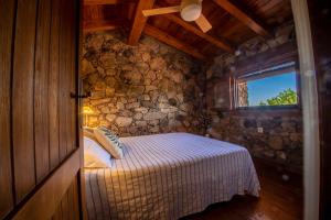 Un dormitorio con una cama y una pared de piedra. en Casa Mimosa, en Candeleda 15 fotos más