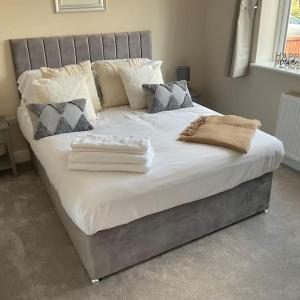 un grande letto con lenzuola e cuscini bianchi di Beautiful Holiday Cottage ad Ashbourne