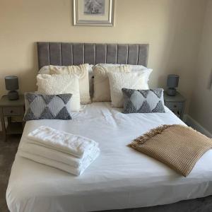 a large bed with white sheets and pillows on it at Beautiful Holiday Cottage in Ashbourne