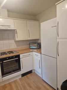een keuken met witte kasten, een fornuis en een koelkast bij 2 Bed 2 Bath Ensuite - FREE secure parking in Birmingham